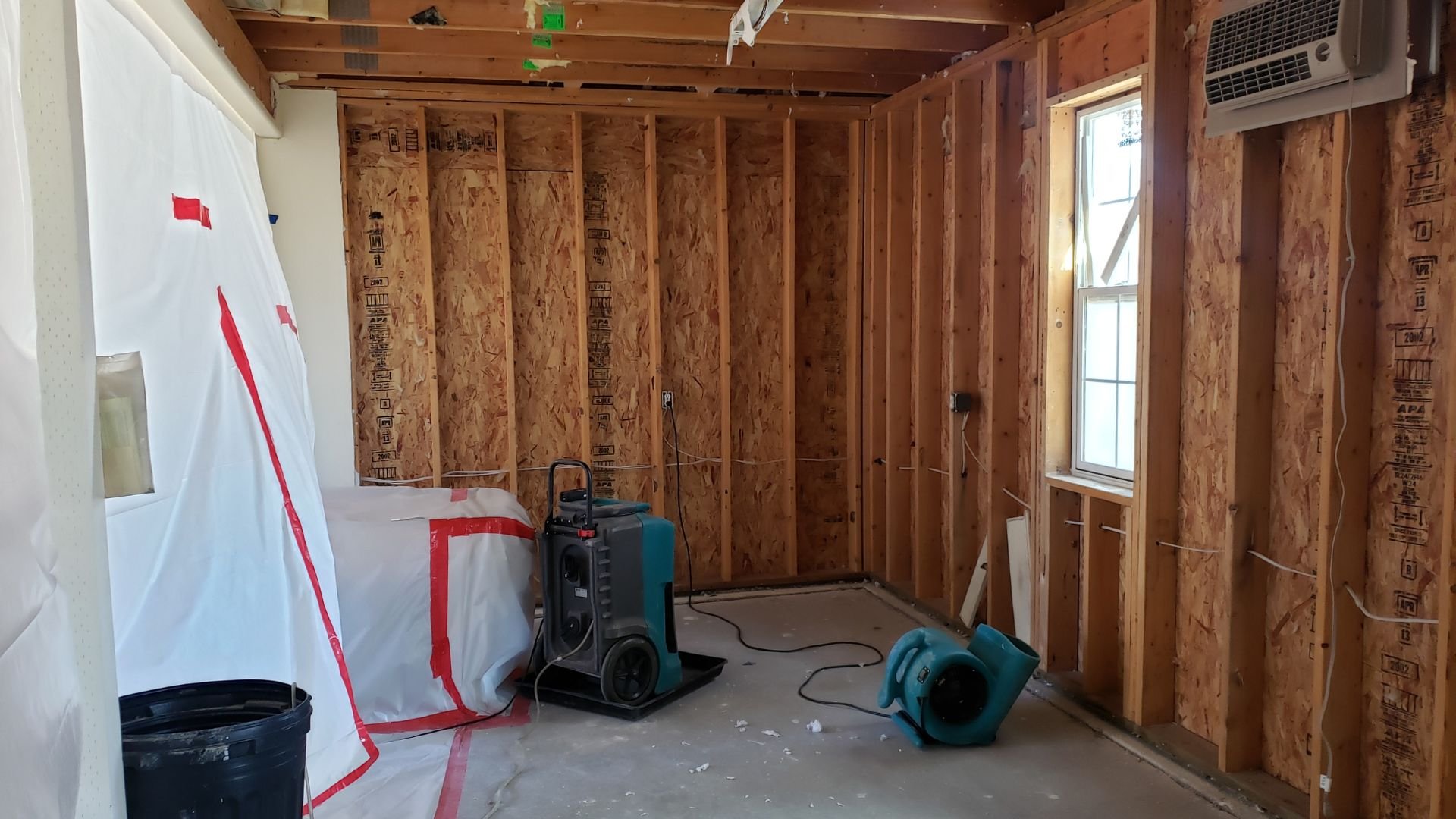 Interior room under construction with exposed wood framing and drying equipment
