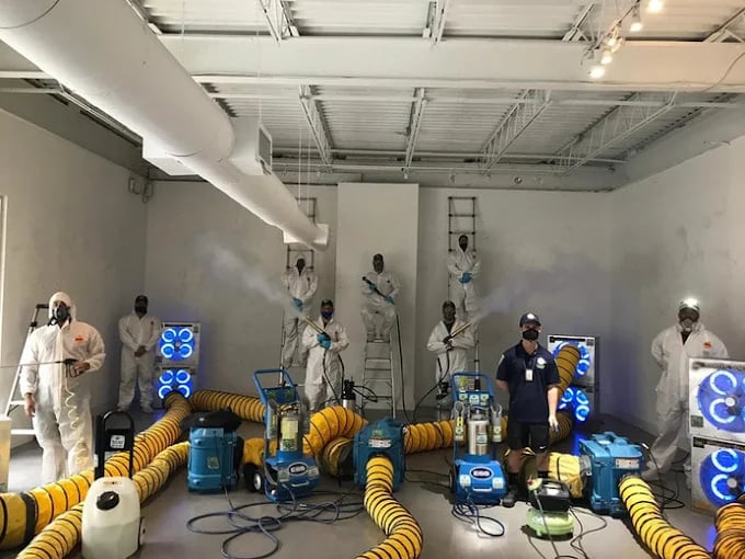 Hazmat team with industrial cleaning equipment in sterile white room