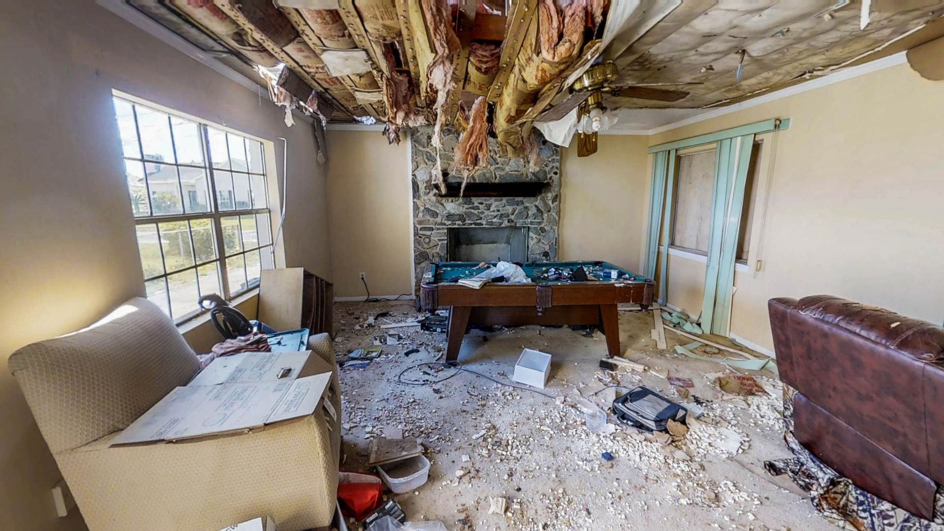 Severely damaged interior room with collapsed ceiling and scattered debris