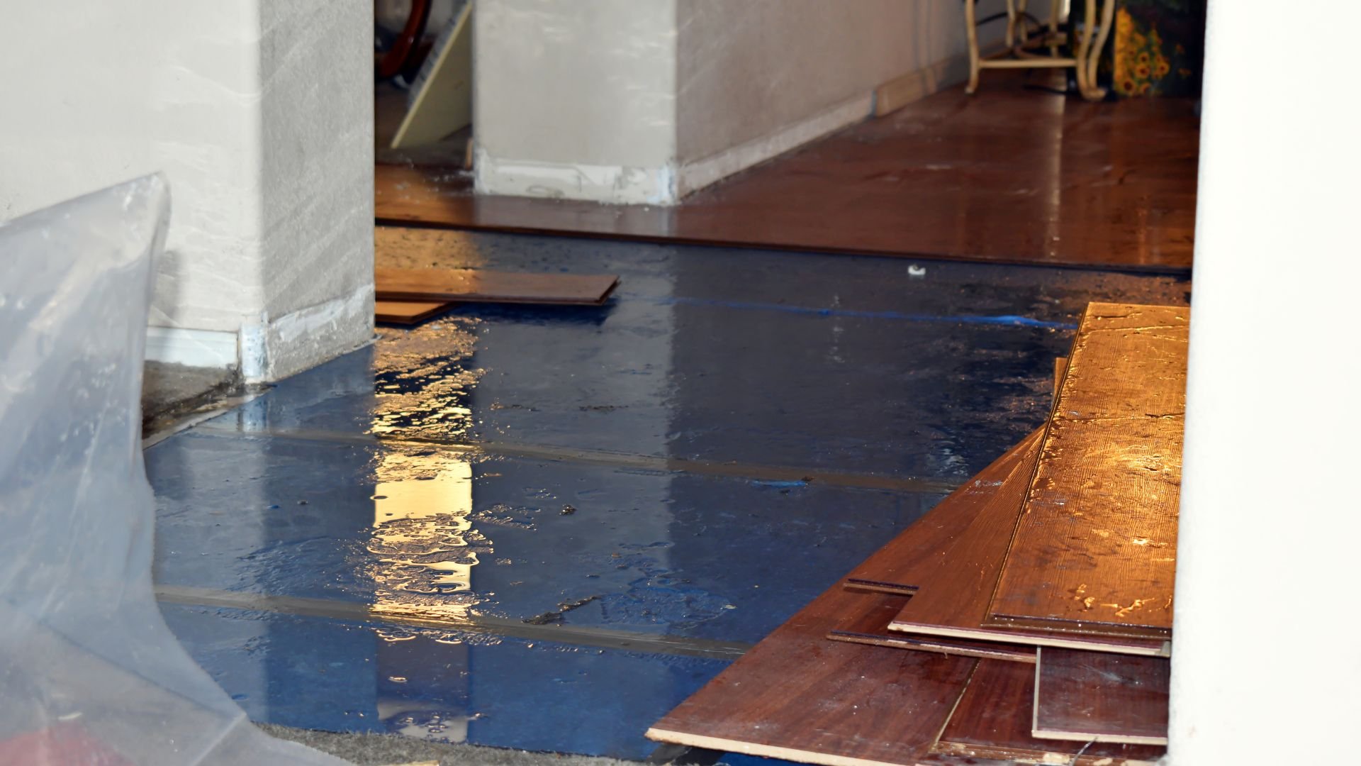 Water damage on wooden floor with puddles and warped planks