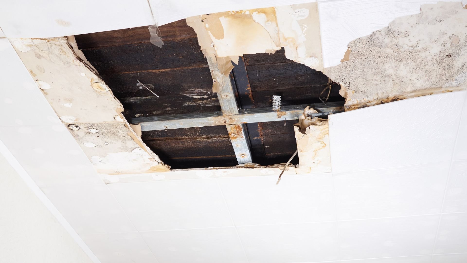 Damaged ceiling with broken wooden beams and water stains