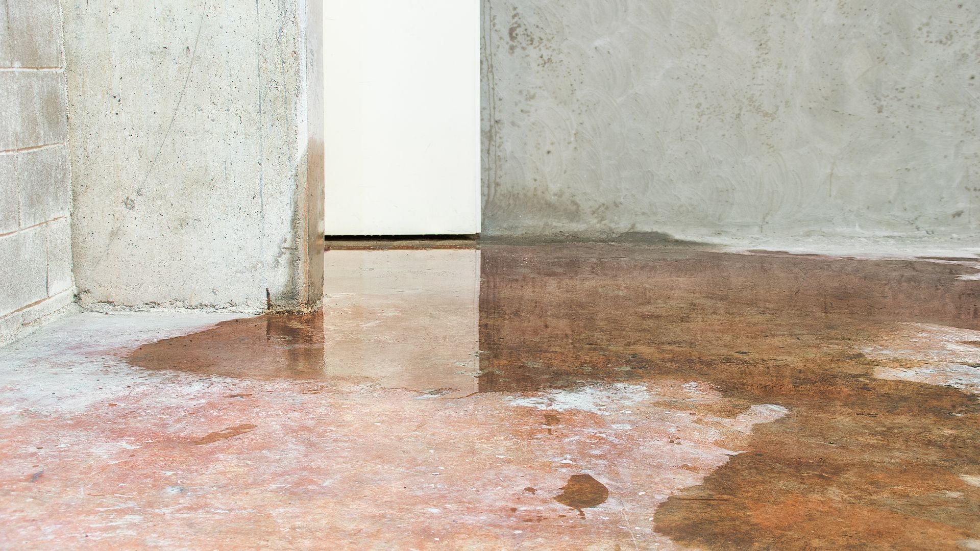 Water damaged concrete floor with wet stains and moisture patches